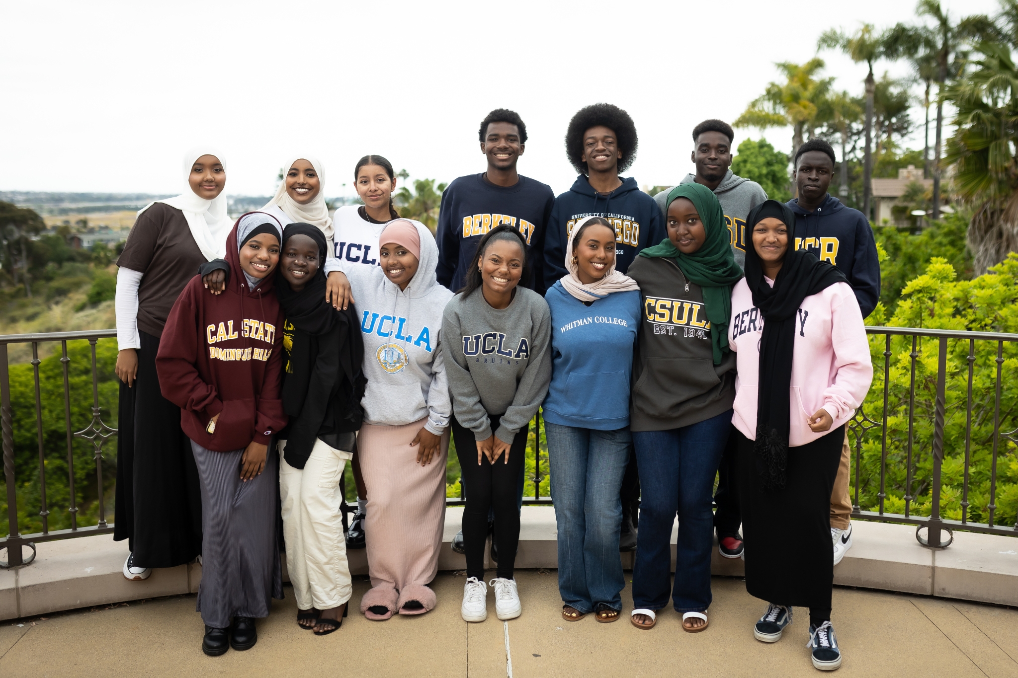 First Gen Scholars: A group of young people in college sweatshirts smile into the camera