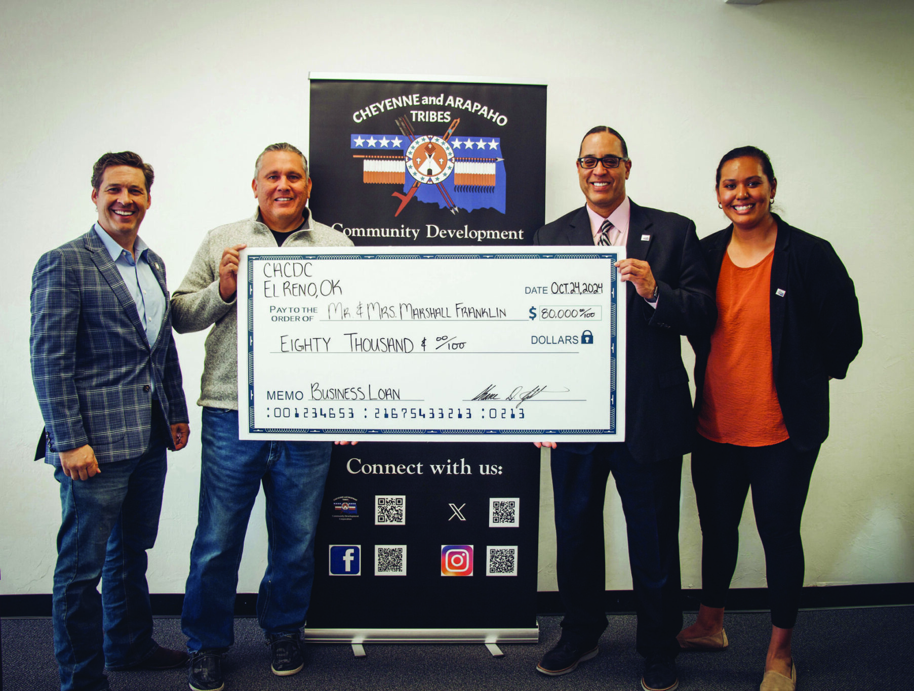 Four people holding a giant check pose for the camera