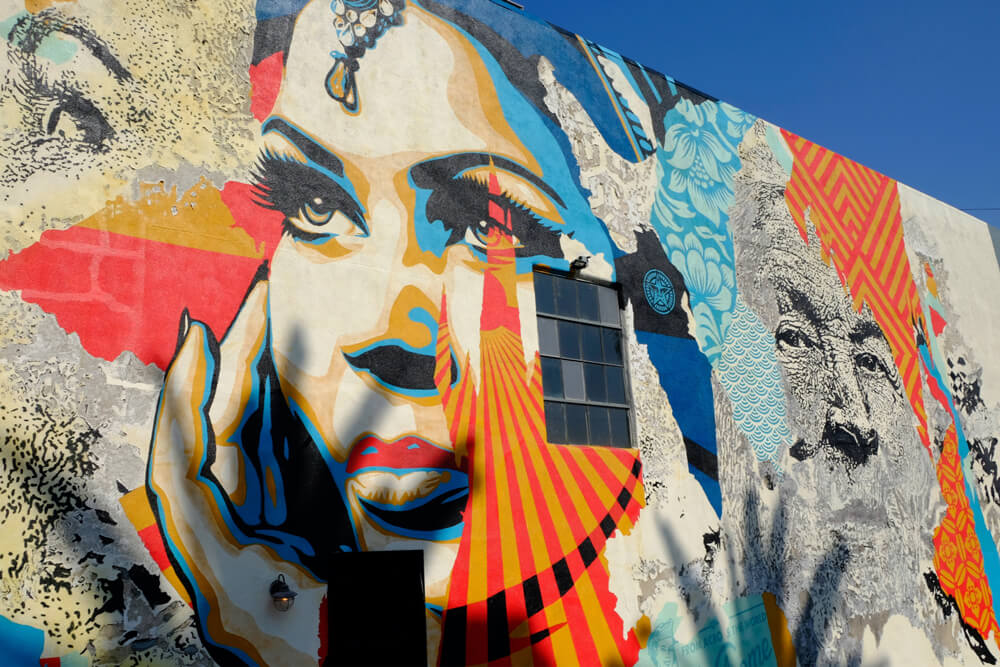 A colorful wall mural depicting a woman with a hand cupping her face