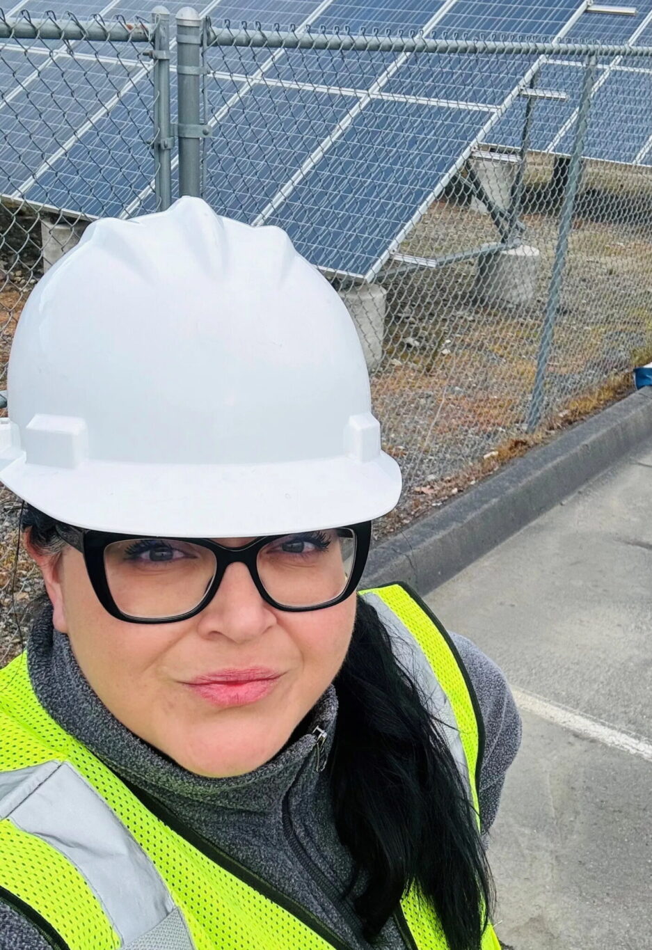 Selfie of a woman wearing a hard hat and safety vest smiling into the camera