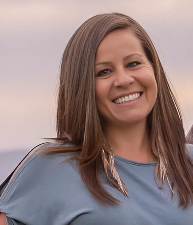 A woman with long brown hair smiles into the camera